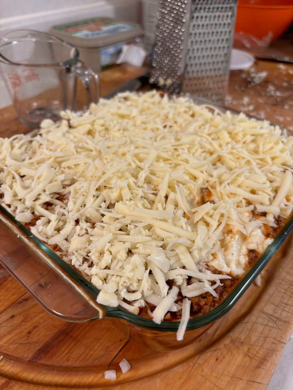 Homemade lasagna in a glass baking dish topped with shredded mozzarella, ready for the oven
