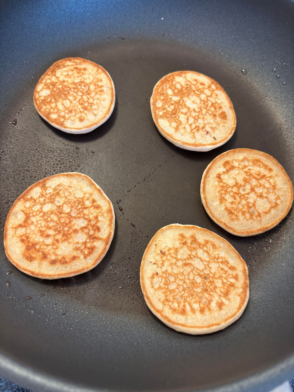 Golden cinnamon vanilla pancakes cooking in a non-stick pan